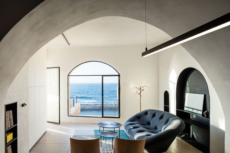 The living room is light-filled, with modern upholstered furniture and stunning sea views