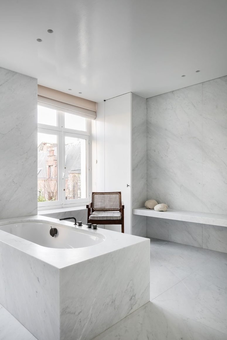 The bathroom is clad with white marble, it's filled with natural light through the window and there's much space
