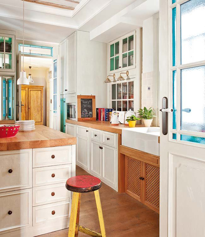 The kitchen is vintage meets mid century modern, with traditional white cabinets and warm wood counters