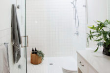 08 The bathroom is clad with white tiles, square and hexagon ones, there’s a cute wooden stool right in the shower