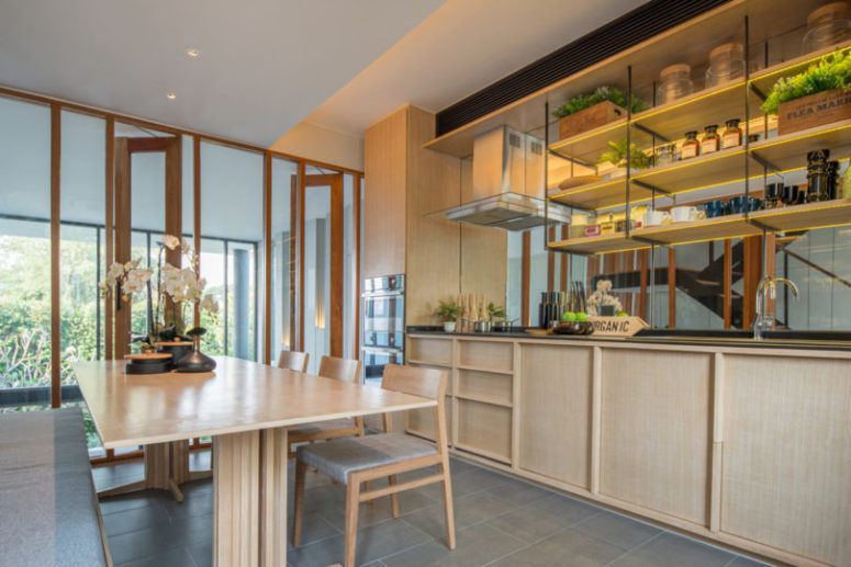 The kitchen is fully clad in light-colored wood, which makes it cozy and inviting and a glazed wall fills it with light