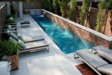 08 a modern small backyard with a narrow pool with waterfall and a couple of loungers
