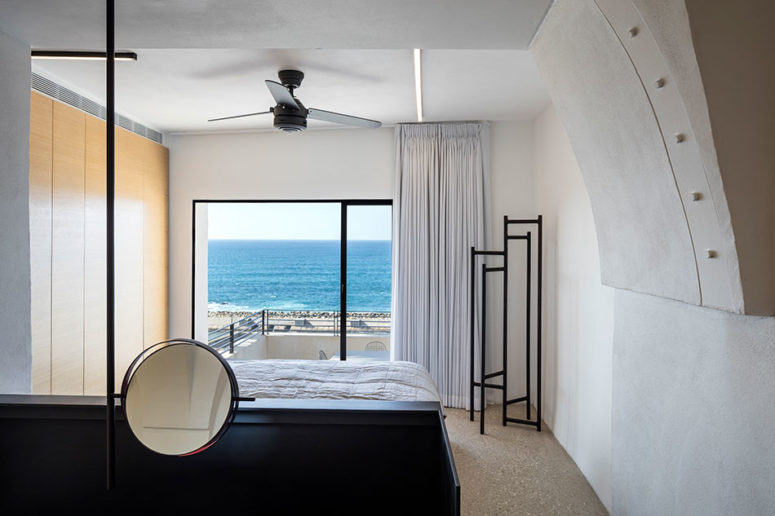 The bedroom is white, with a black bed, eye-catchy black clothes rack and a light veneer wardrobe, the sea view is amazing