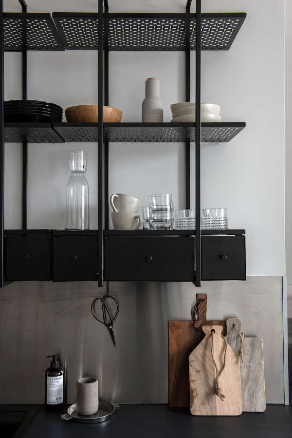 The kitchen cabinets and countertops are made of blackened metal, the shelves have a ligthweight look due to the perforated design