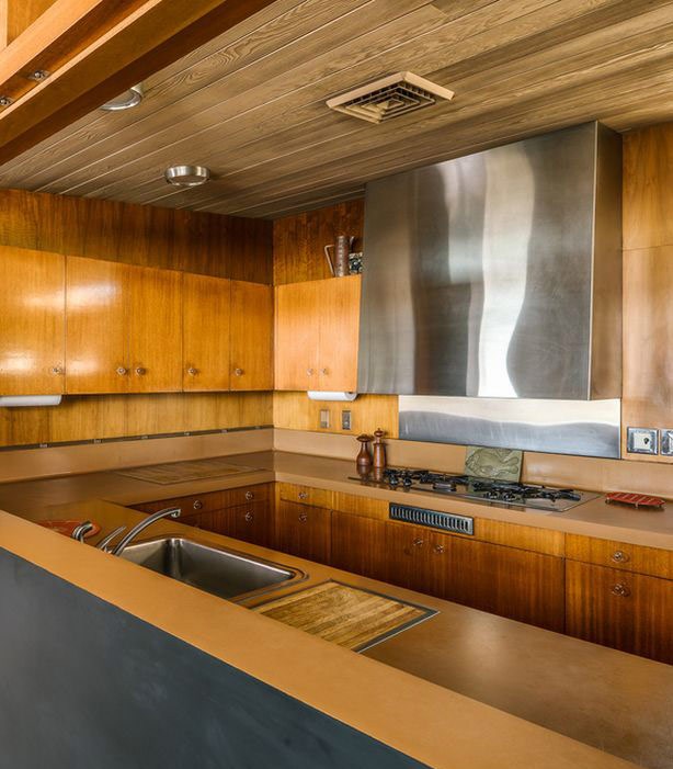 The kitchen is fully clad with amber-colored natural wood and stainless steel touches stand out a lot