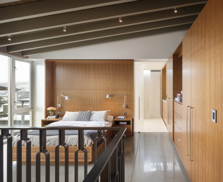 The master bedroom is clad with warm-colored wood and there's a glazed wall to catch the views