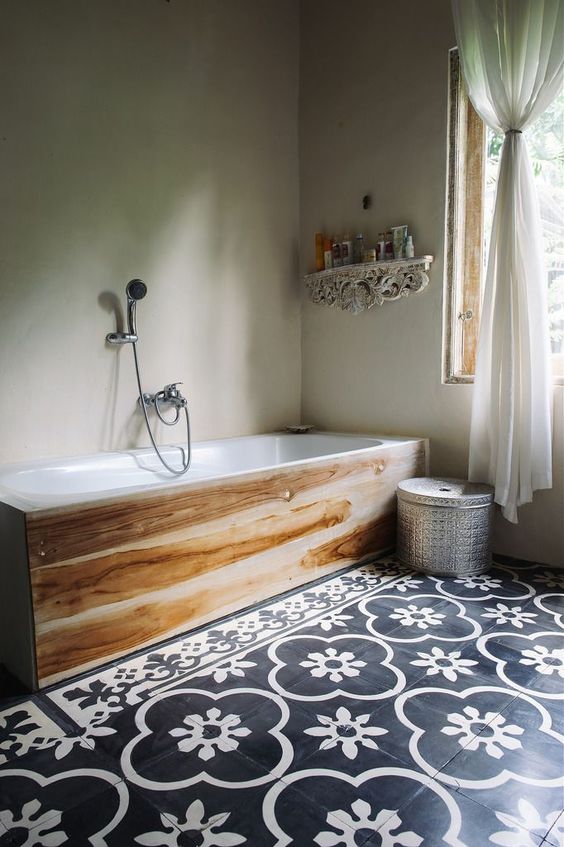 black and white patterned floor tiles and a wood covered bathtub