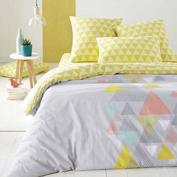 a grey duvet with some muted colored triangles and lime triangle print pillowcases
