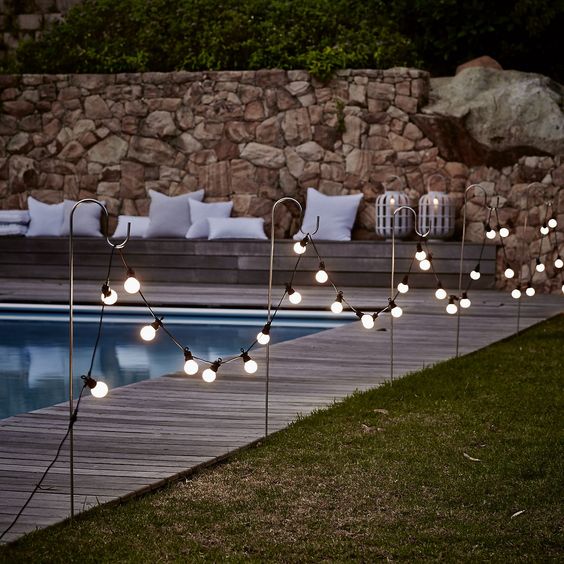 bistro bulb fairylights attached to hooks along the whole pool