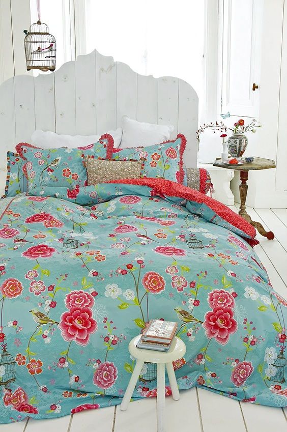 blue bedding with red and fuchsia flowers and red ruffles on the pillowcases