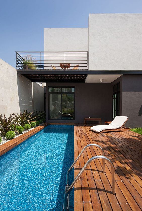 a modern wooden deck with a narrow pool and desert plants lining it