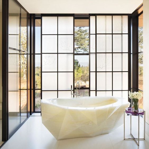 Gorgeous faceted tub carved from white onyx is a wow factor in this bathroom