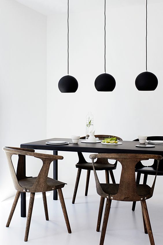 this minimalist dining space is highlighted with matte black pendant lamps