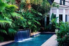 25 brick clad backyard with a lot of greenery for privacy and a narrow pool with waterfalls