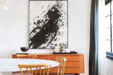29 a black and white splatter artwork in a mid-century modern dining space