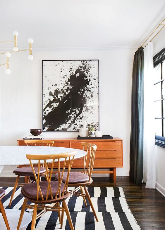 A black and white splatter artwork in a mid century modern dining space