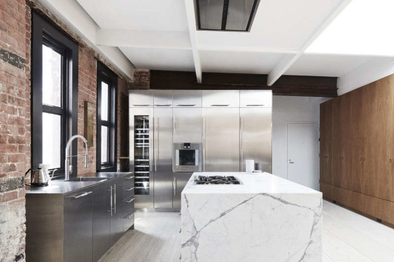 The kitchen features stainless steel cabinets, wooden tall ones for storage and a large marble kitchen island