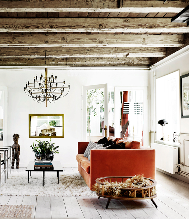 The living room features wooden beams and a bold orange sofa, fur pieces add coziness and texture