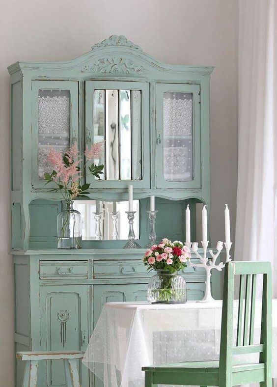 a mint vintage cupboard with mirror parts and tulle curtains inside the compartments