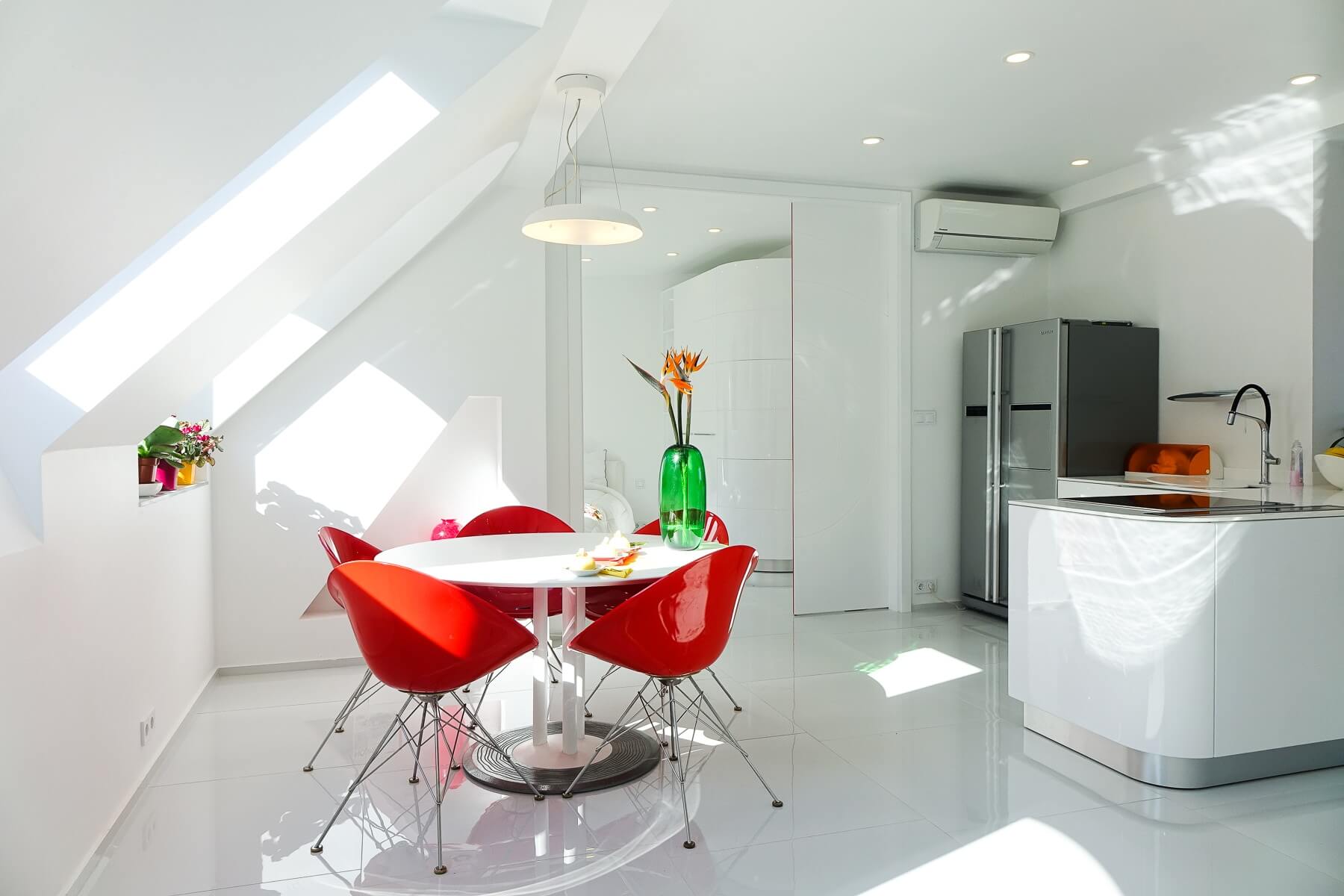 The attic kitchen is all white, with a corner cooking space and a small dining area by the window