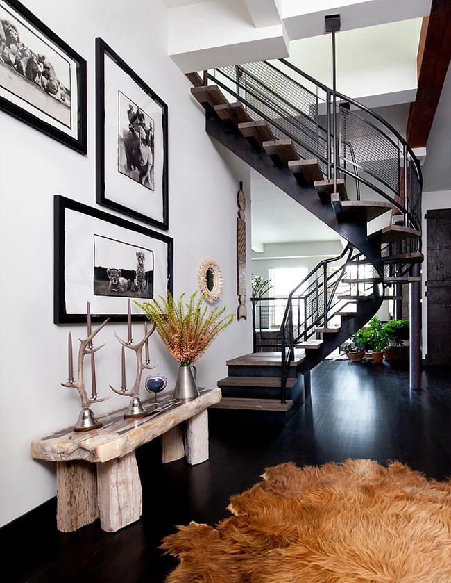 The entryway has a cool staircase, a faux fur rug and a rough wood bench