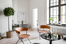 03 The space is flooded with natural light through the large factory windows and copper-colored wooden chairs add interest