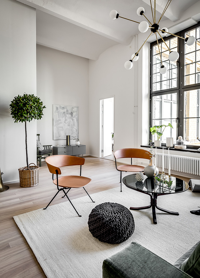 The space is flooded with natural light through the large factory windows and copper colored wooden chairs add interest