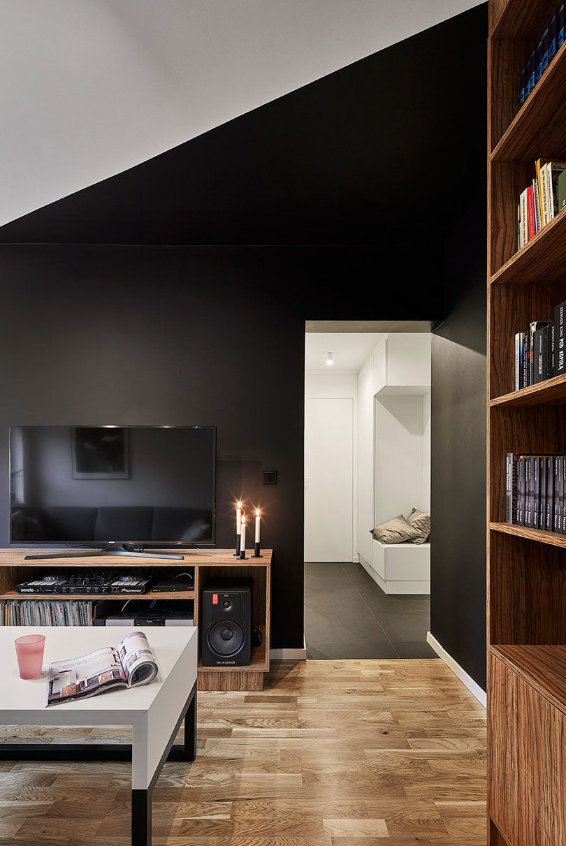 The statement black walls are softened with warm colored wooden furniture