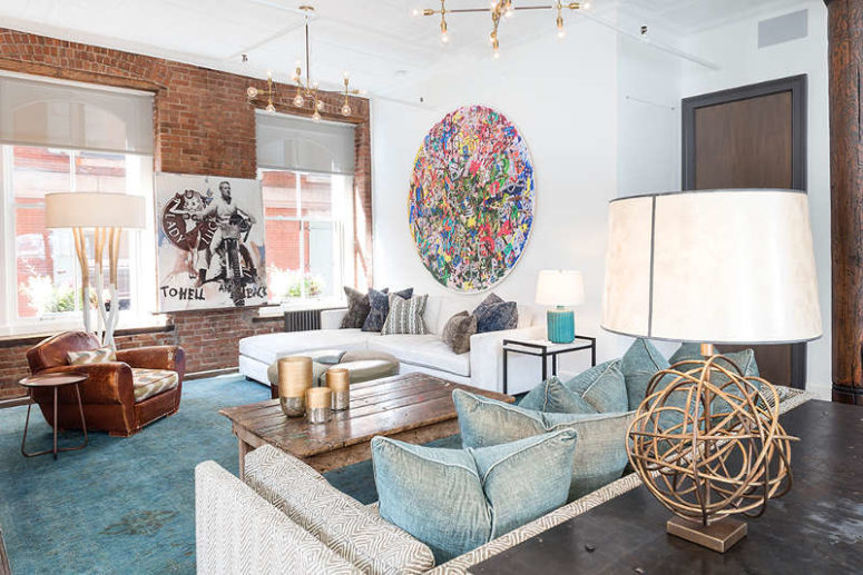 A bold abstract wall art adds eye-catchiness to the space, and a leather chair and a shabby coffee table add texture