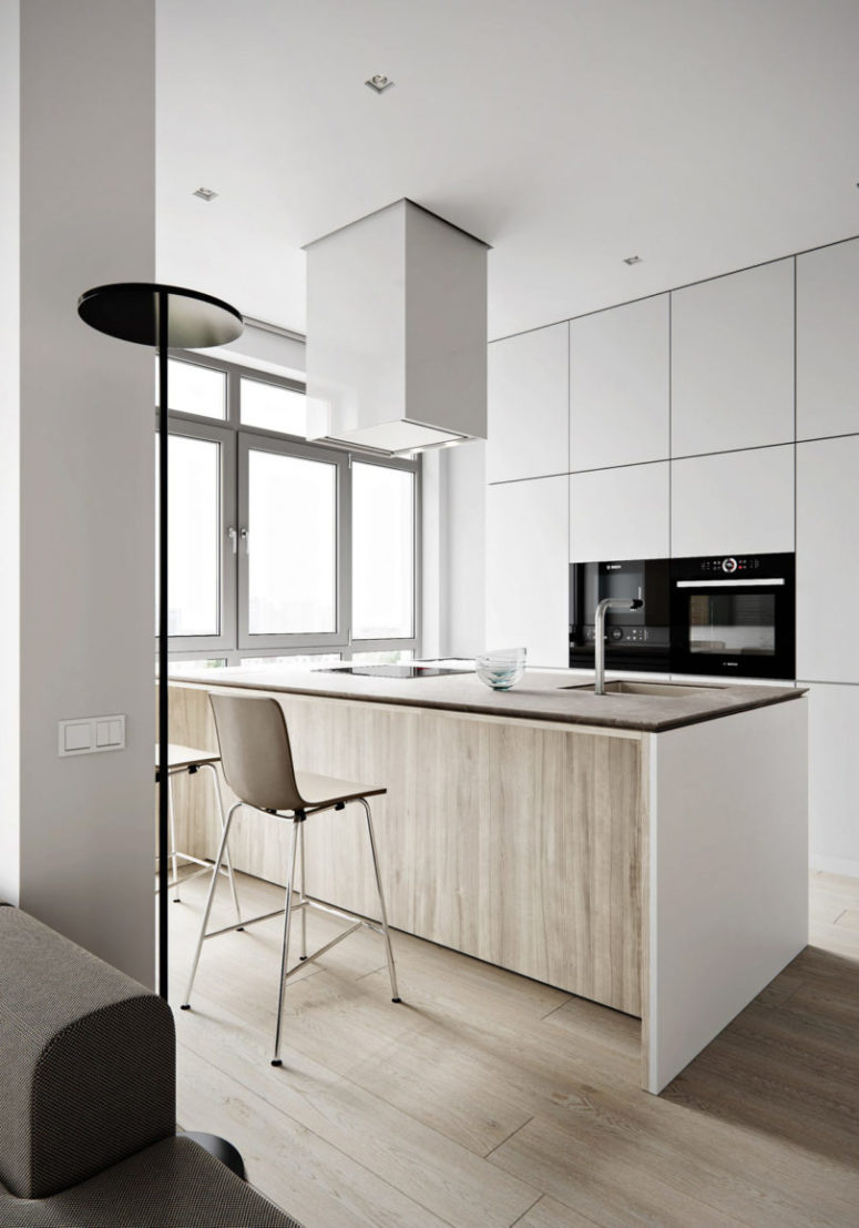 The kitchen features light-colored cabinets with no handles, a large kitchen island that doubles as a dining table