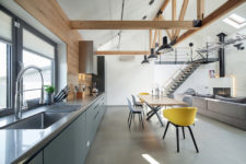 04 The kitchen has large windows and a grey color palette, while the dining space is accentuated with bold yellow chairs