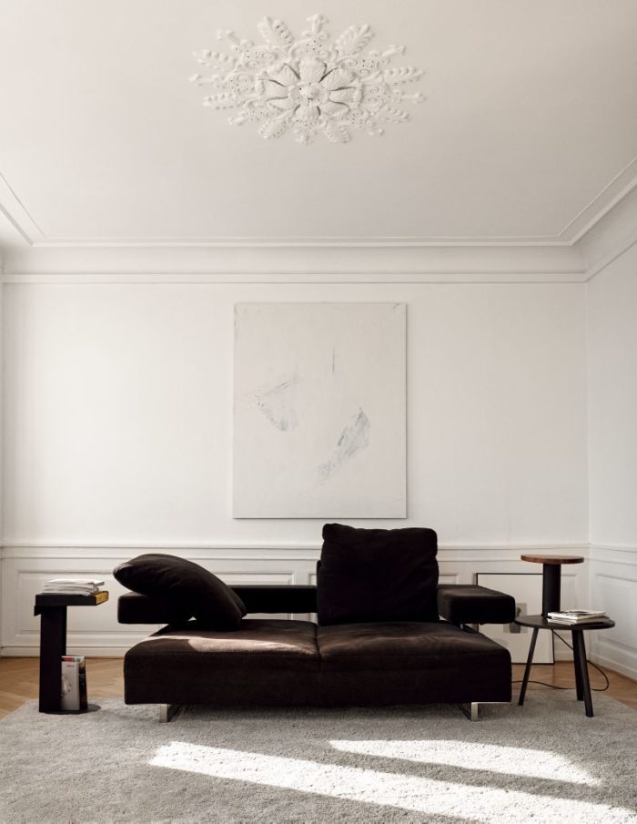 The living room features a gorgeous stucco ceiling, and a black sofa and a fluffy rug give texture and make it more inviting