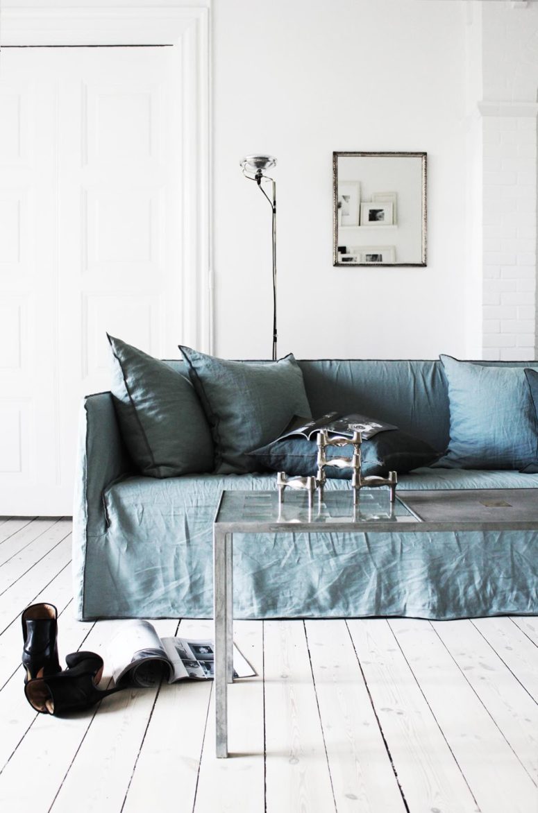 There are some colorful touches done with furniture, for example, this dusty blue sofa with pillows, which perfectly accentuates the space