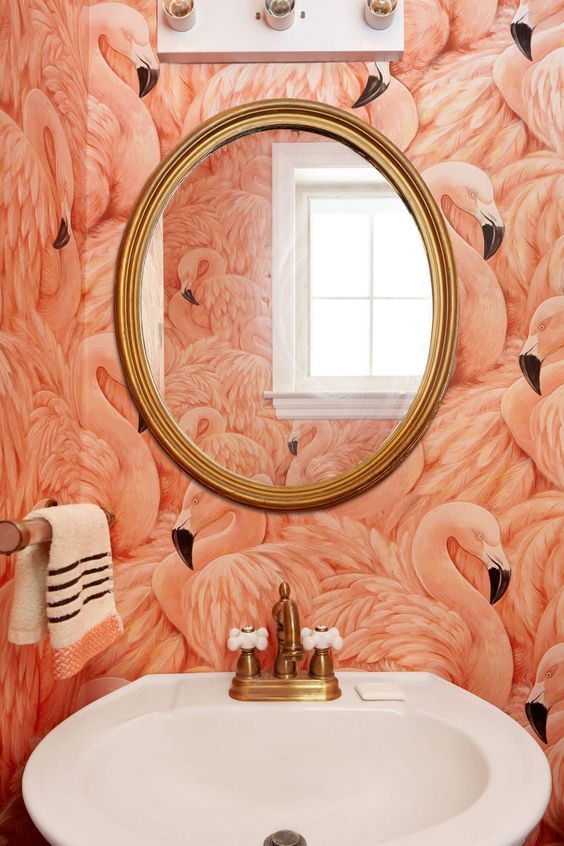 coral flamingo wallpaper in a powder room looks interesting with gold fixtures