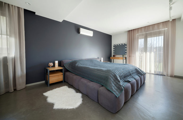 the master bedroom is spacious and has a unique upholstered bed and again a grey color palette
