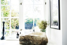 The bathroom has framed windows and a stunning rough wood sink contrasting with modern surroundings