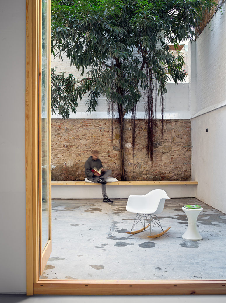 The patio is decorated in a minimalist way, with a long wooden bench and some modern furniture
