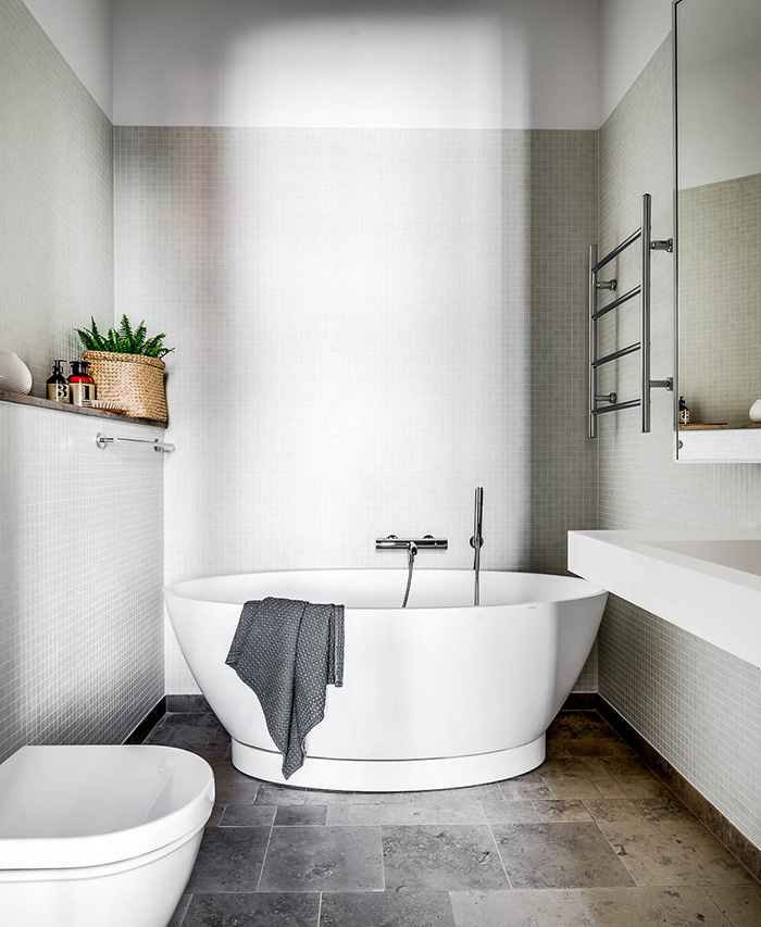 The bathroom is small yet very relaxing, with an oval-shaped bathtub and dove grey tiles