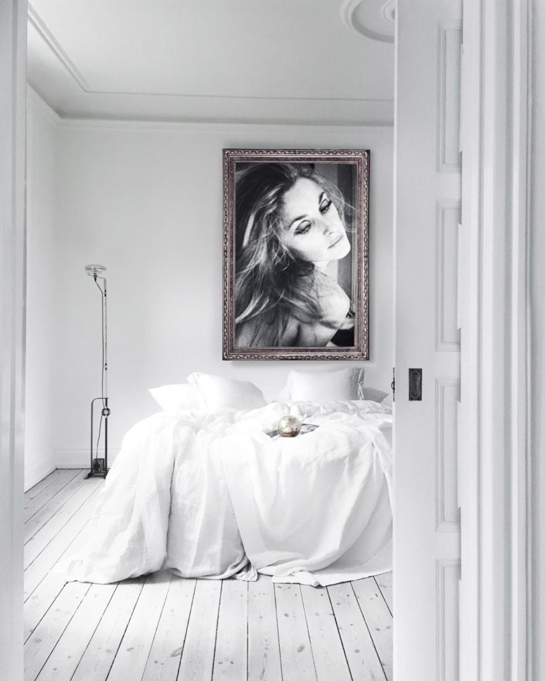 The master bedroom features a large comfy bed and an oversized framed portrait of the owner, which makes the space gorgeous and refined