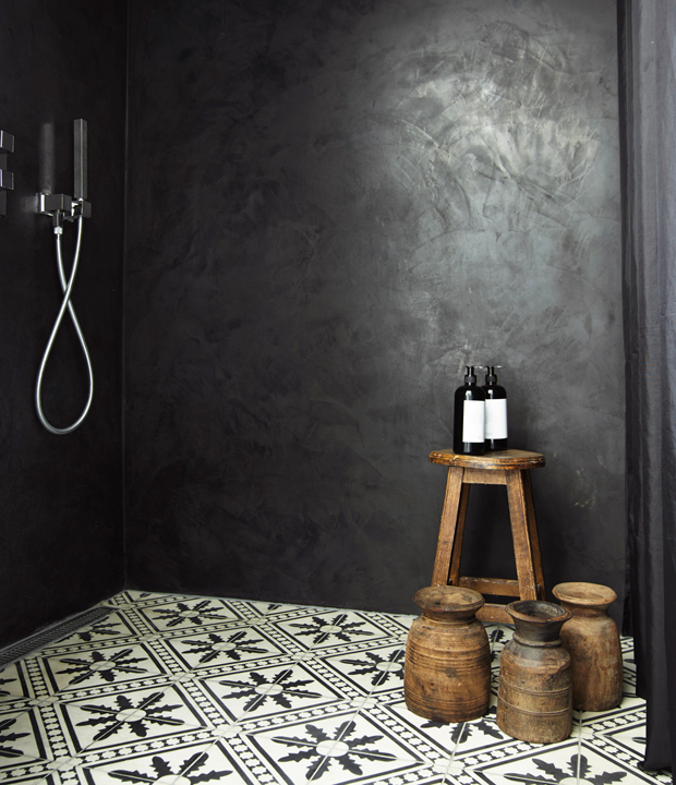 The shower is done in black and graphic floor tiles, wooden accessories add warmth