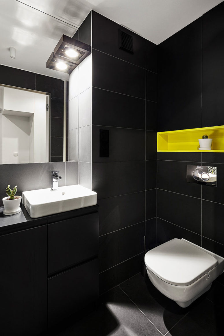 The matte black monochromy is broken with a neon yellow built-in shelf over the toilet