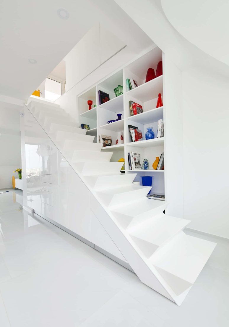 A large staircase in white leads up and there's a large storage unit on the right