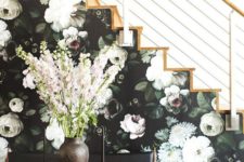 11 a side of the stairs covered with moody floral wallpaper in dark greens and neutrals