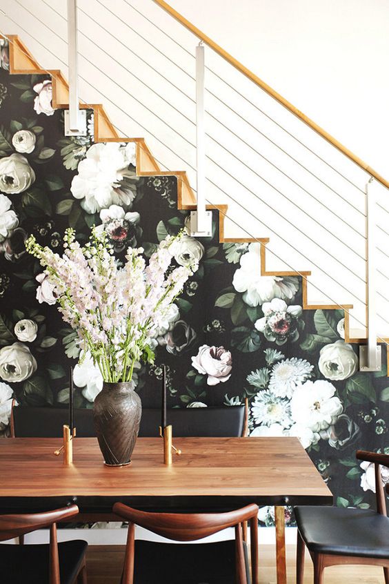 a side of the stairs covered with moody floral wallpaper in dark greens and neutrals
