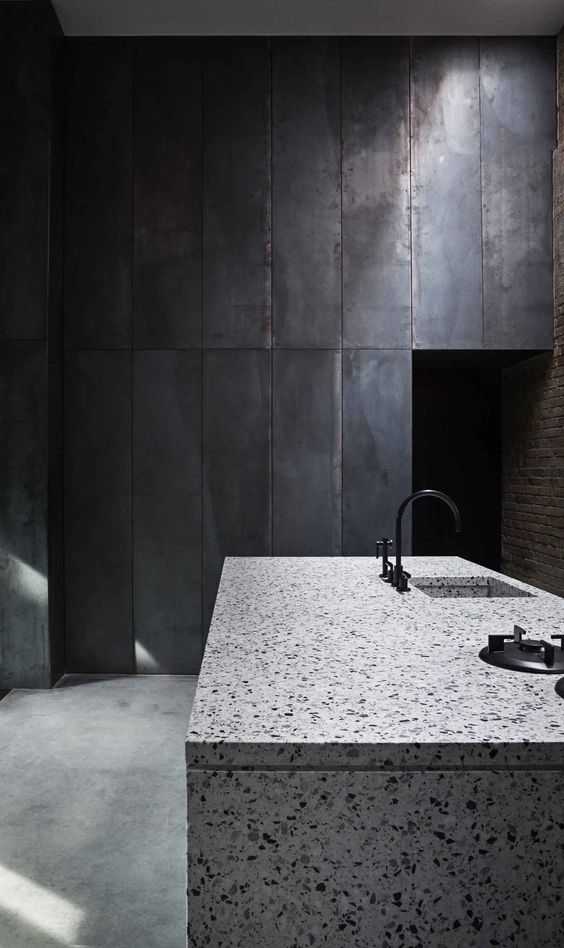 a white terrazzo kitchen island looks contrasting in this moody kitchen