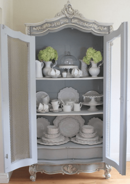 a grey vintage cupboard with chicken wire on the whole length of doors