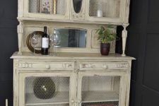 20 a warm pastel cupboard with chicken wire in compartment doors to see the objects better