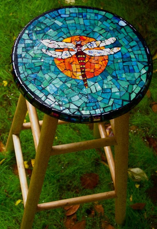 a wooden stool with a colorful dragonfly mosaic on top for a cool look
