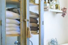 24 a vintage blue and cream cupboard with chicken wire for storing bathroom towels and other stuff