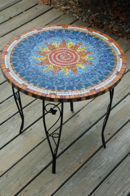 pretty outdoor table with a colorful sun mosaics and on forged legs